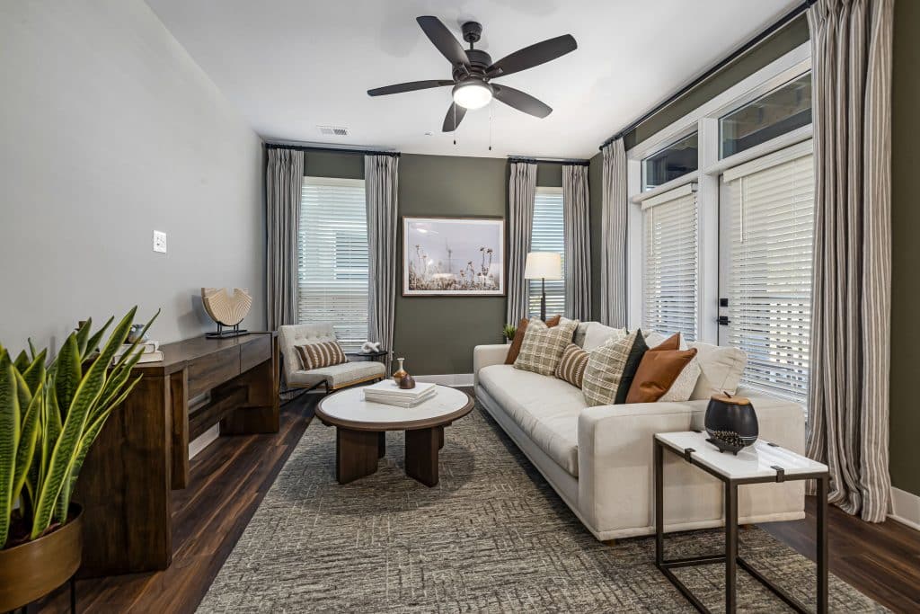 LIving room with overhead fan large windows and patio doors